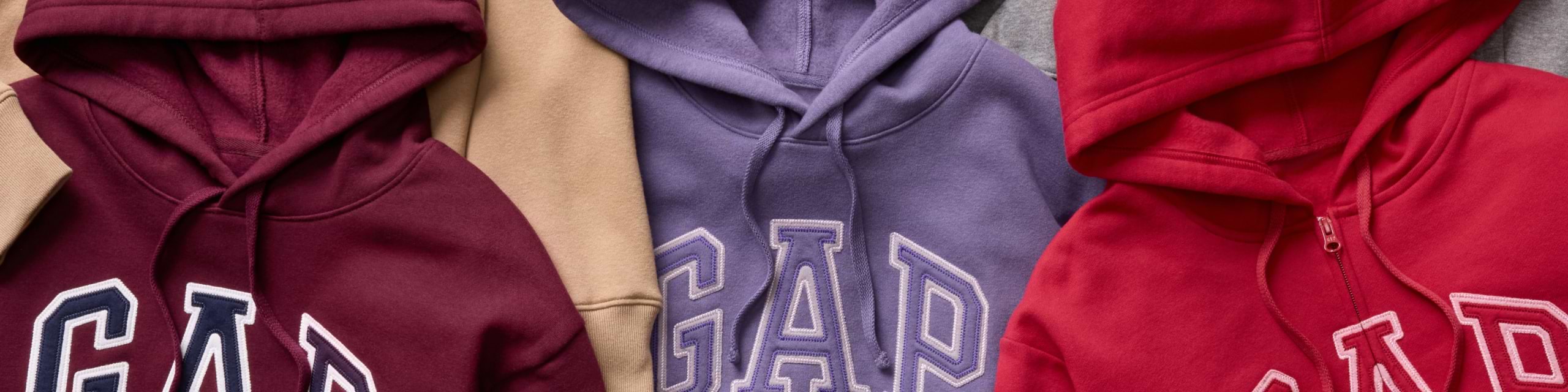 Close-up of GAP logo hoodies in burgundy, lavender, and red laid side by side.