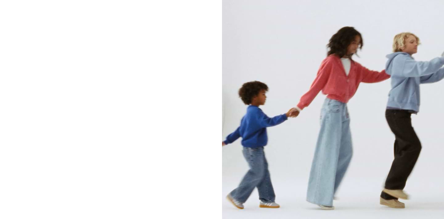 Three people, including a child, walk in a line holding hands against a white background.