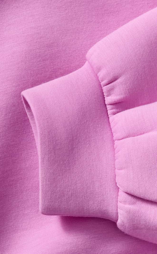 Close-up of a light pink sweatshirt sleeve with a ribbed, elastic cuff.