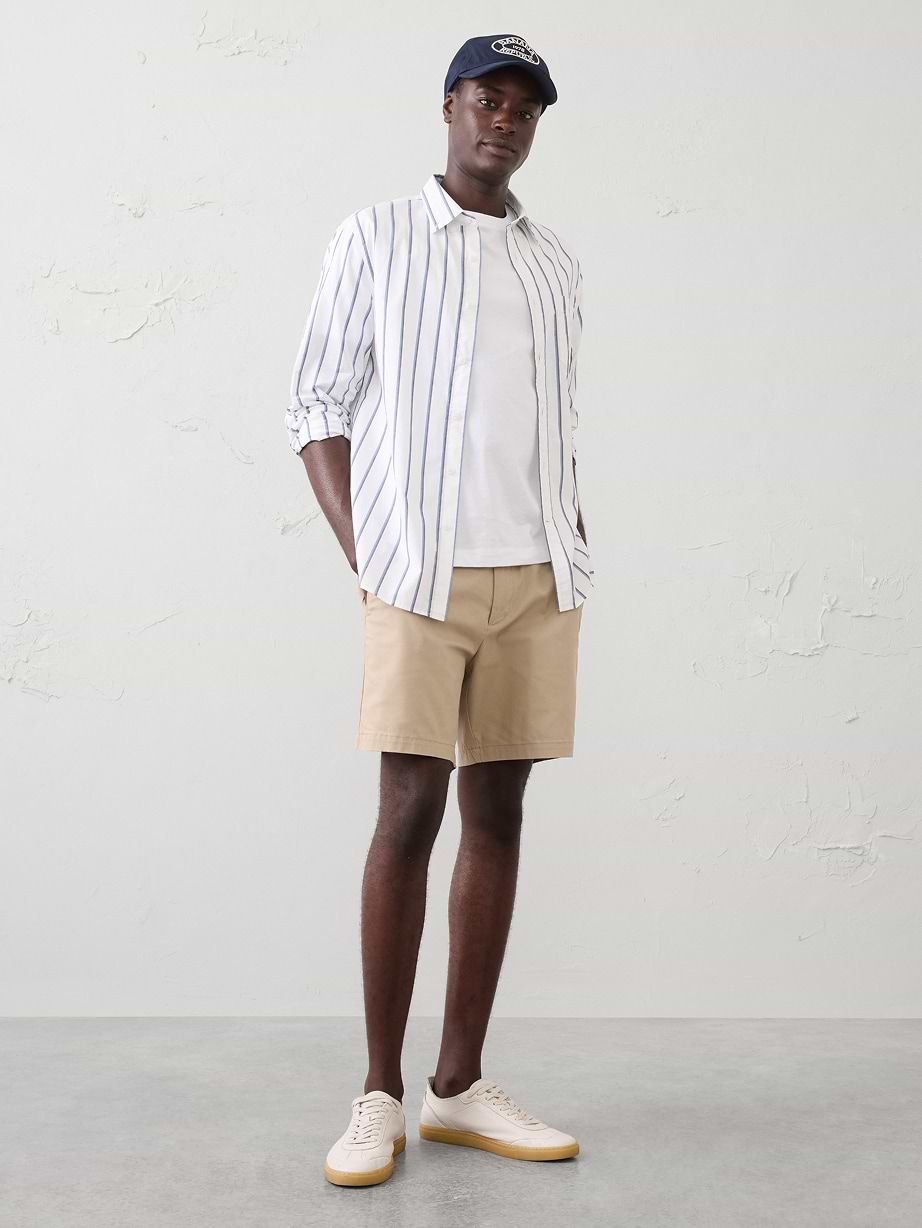 Man in striped shirt, white t-shirt, and tan shorts with a cap.