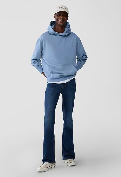 A male model wearing boot-cut jeans and an Old Navy logo hoodie.