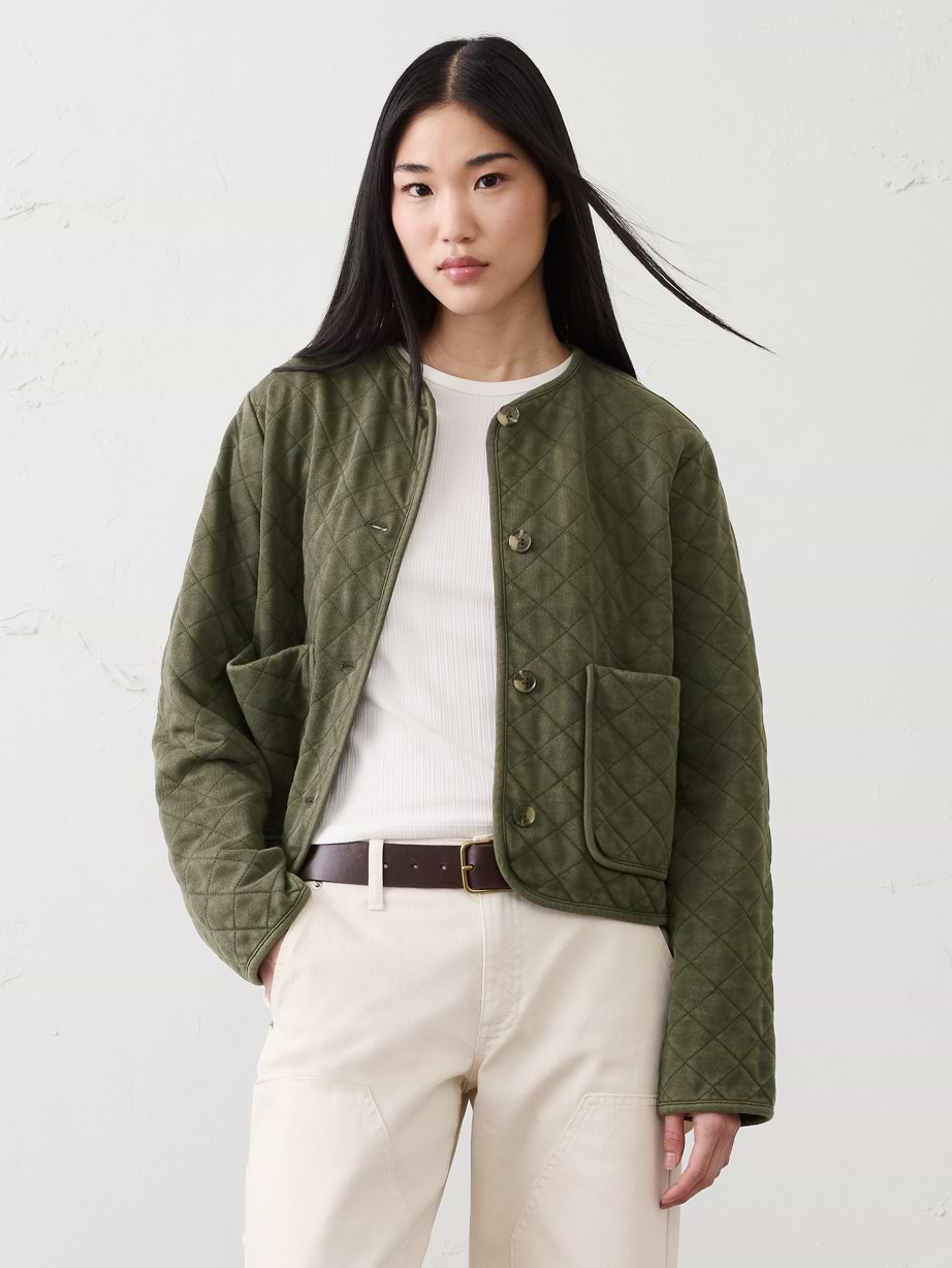 Woman in green jacket, white tshirt and jeans.