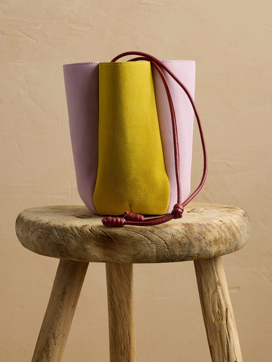 Pink and yellow bucket bag on a wooden stool.