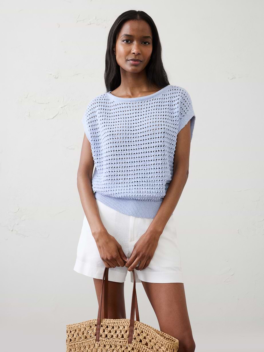 Woman in blue sweater top and shorts.