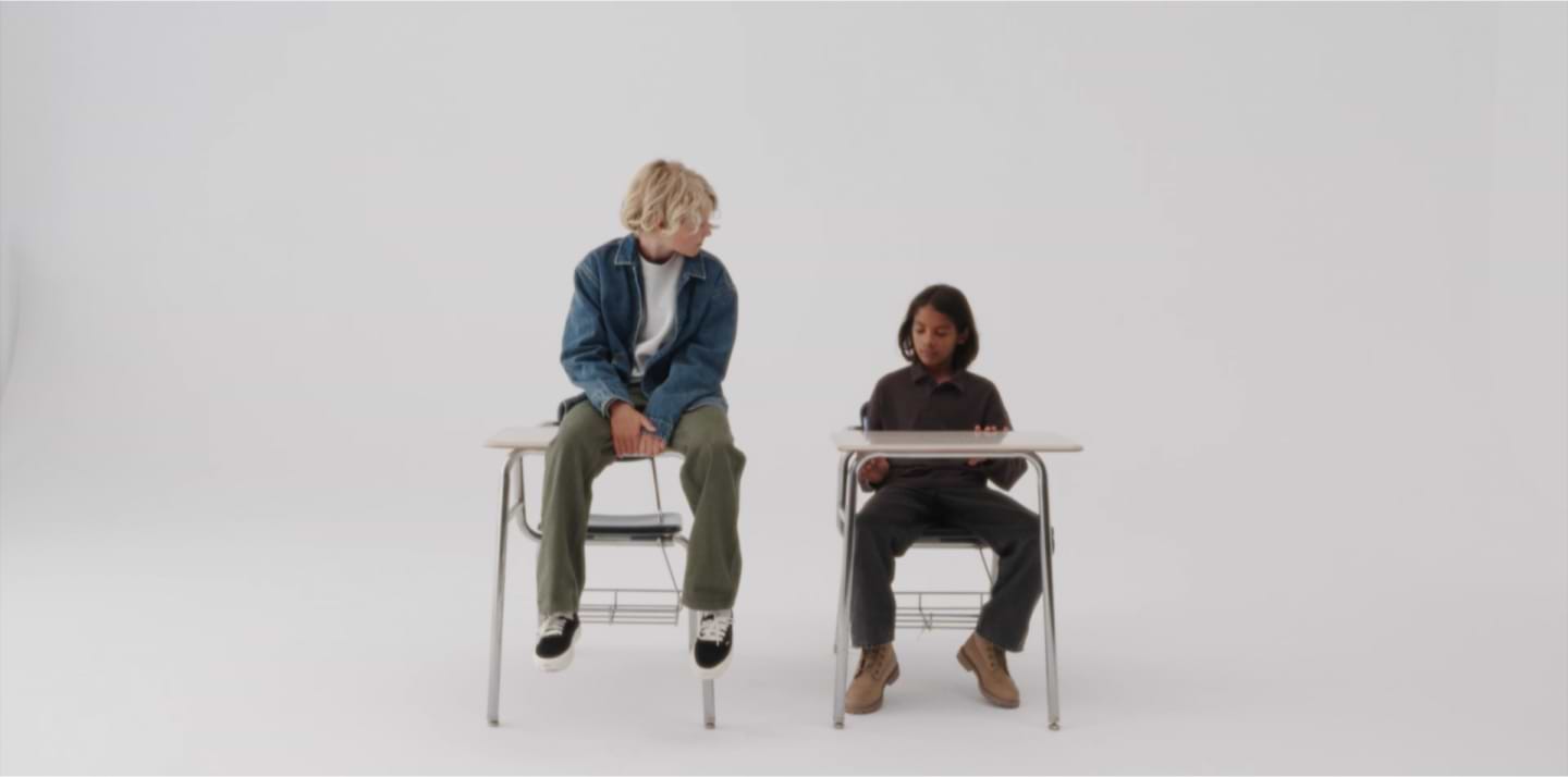 two people sitting at desks in a white room