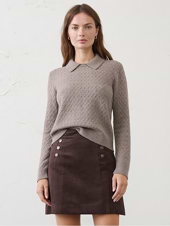 Model wearing a taupe collared knit sweater and a dark brown buttoned mini skirt against a plain light background.