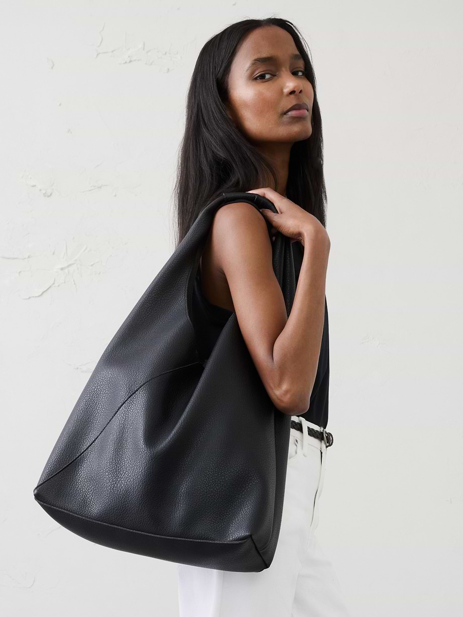 Woman in black top, white jeans, and black purse.