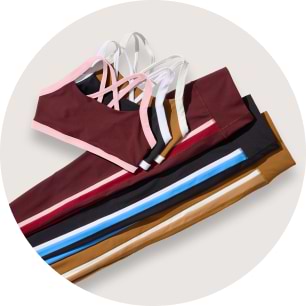 Strappy sports bras and leggings stacked in burgundy, black, tan, and blue.