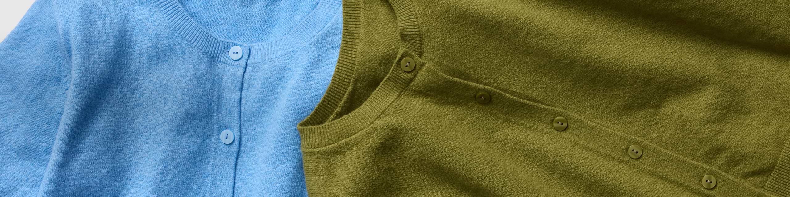 Close-up of light blue and olive-green knit button-front cardigans.