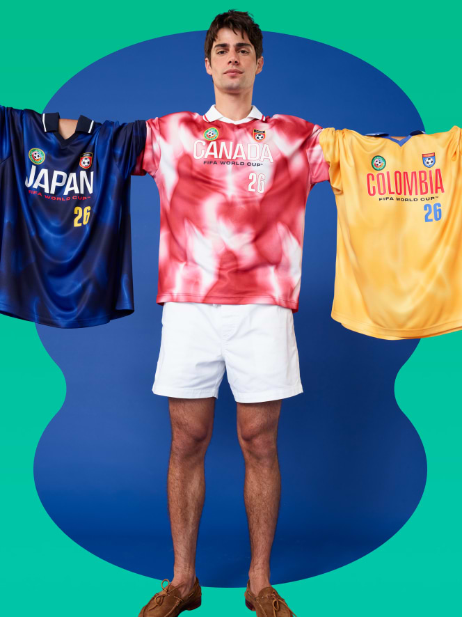 Male model holding soccer jerseys from Japan, Canada and Columbia.