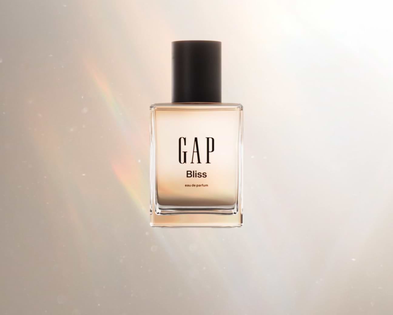 Square glass perfume bottle labeled “GAP Bliss” with a black cap on a soft, glowing background.