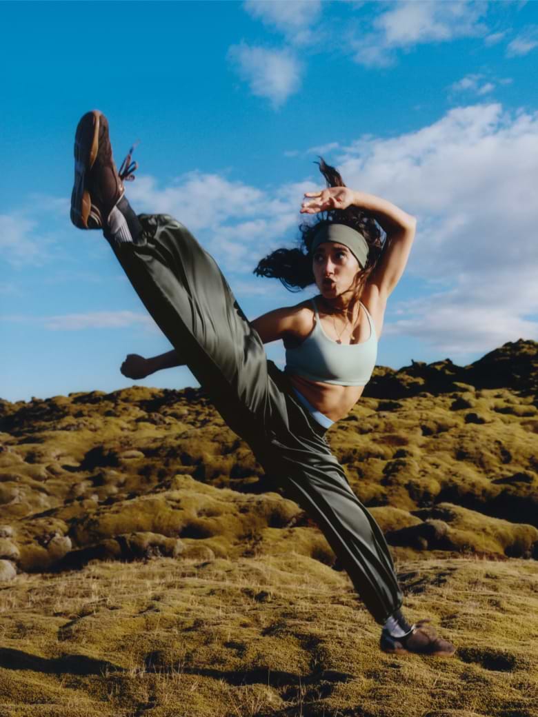 a woman in a green top doing a kick in the air