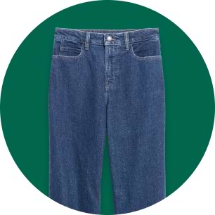 Blue denim jeans with five-pocket design on a green background.