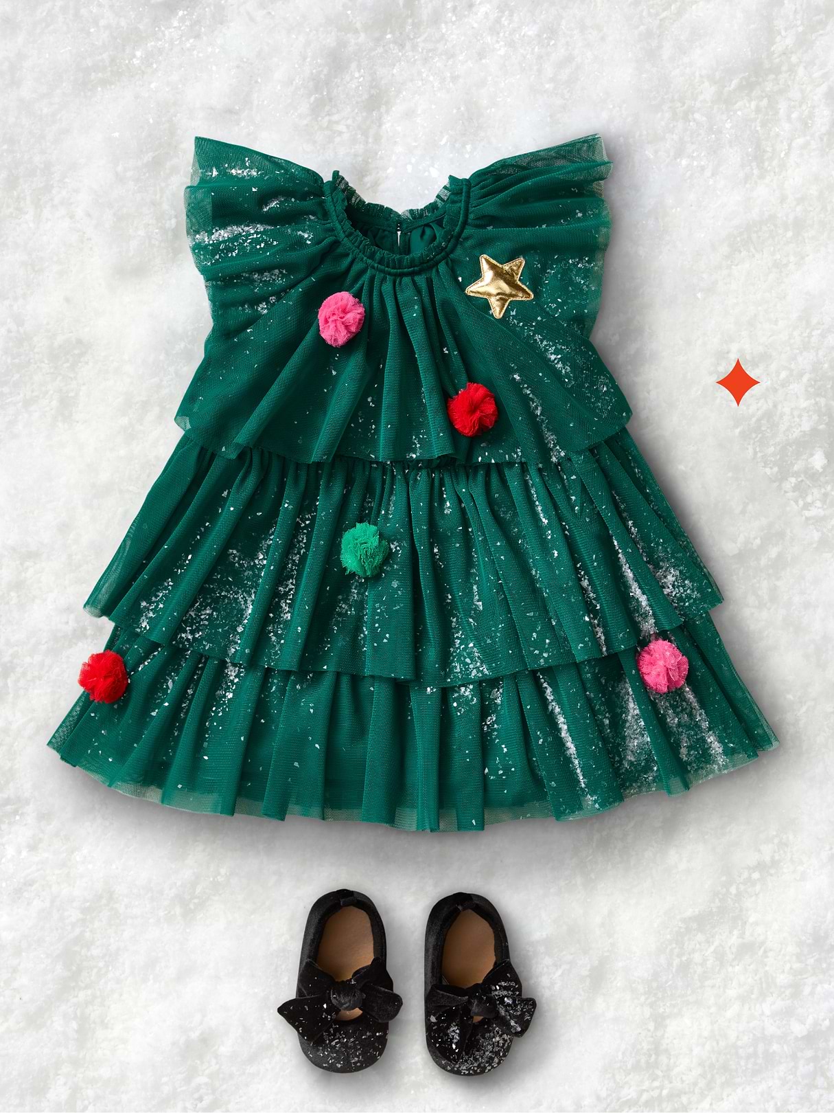 a baby's christmas dress and shoes are laid out on the snow