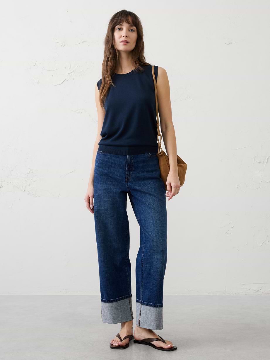 Woman in blue top and cuffed jeans.
