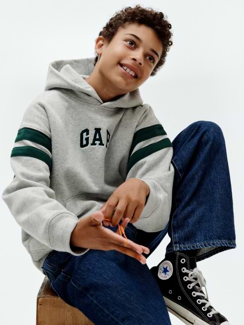 a boy sitting on a stool with his hands on his knees