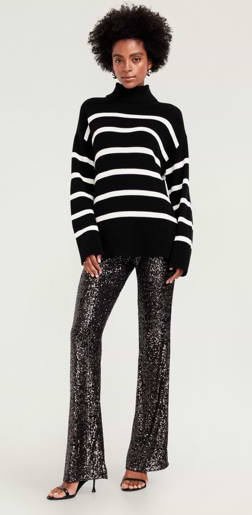 Une femme vêtue d’un pantalon noir scintillant à paillettes, agencé à un chandail et des chaussures à talon à brides.