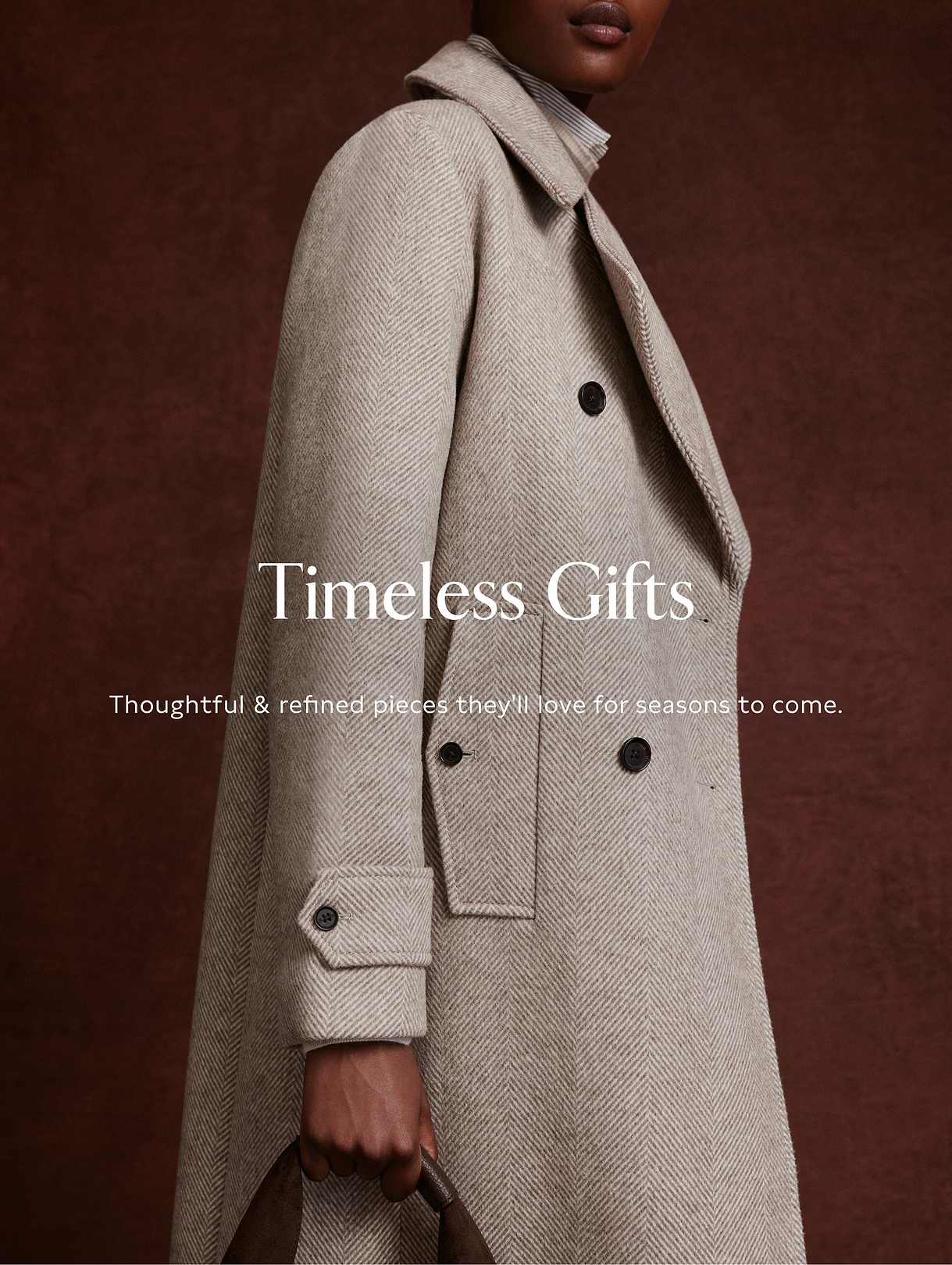 Close-up of a person in a light beige herringbone overcoat holding a brown bag, with overlay text: “Timeless Gifts—Thoughtful & refined pieces they’ll love for seasons to come.”