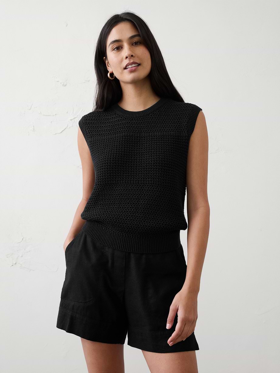 Woman in black sleeveless sweater and shorts.