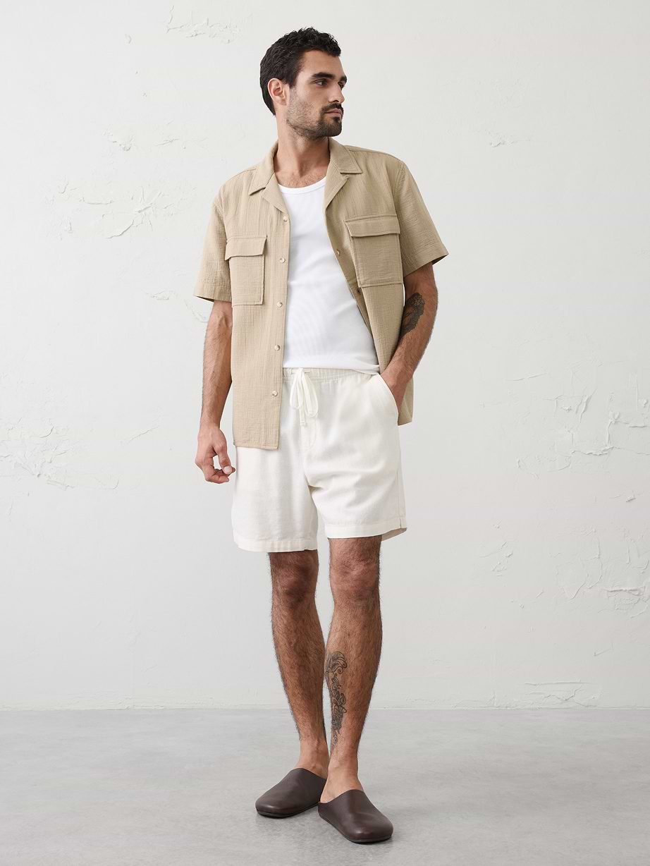 Man in tan shirt, layered over white tshirt and white shorts.