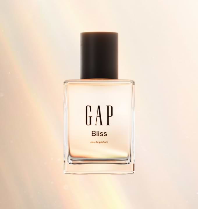 Clear rectangular perfume bottle with black cap labeled “GAP Bliss eau de parfum” against a soft pastel light background.