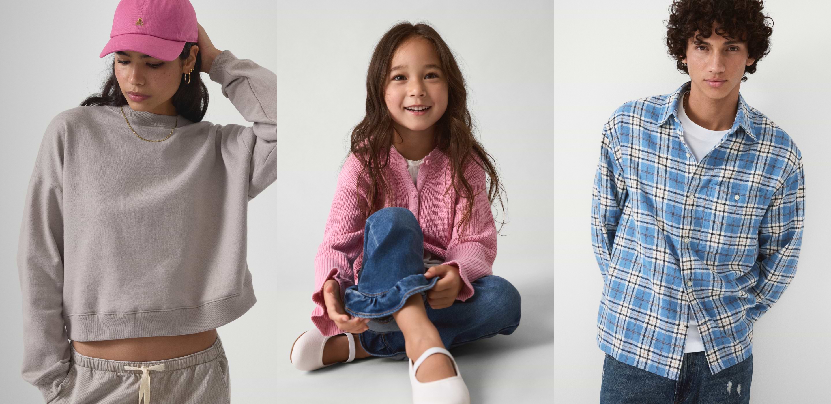 Three models in casual wear: left in gray sweatshirt with pink cap; center child in pink sweater and jeans; right in blue plaid shirt and jeans.