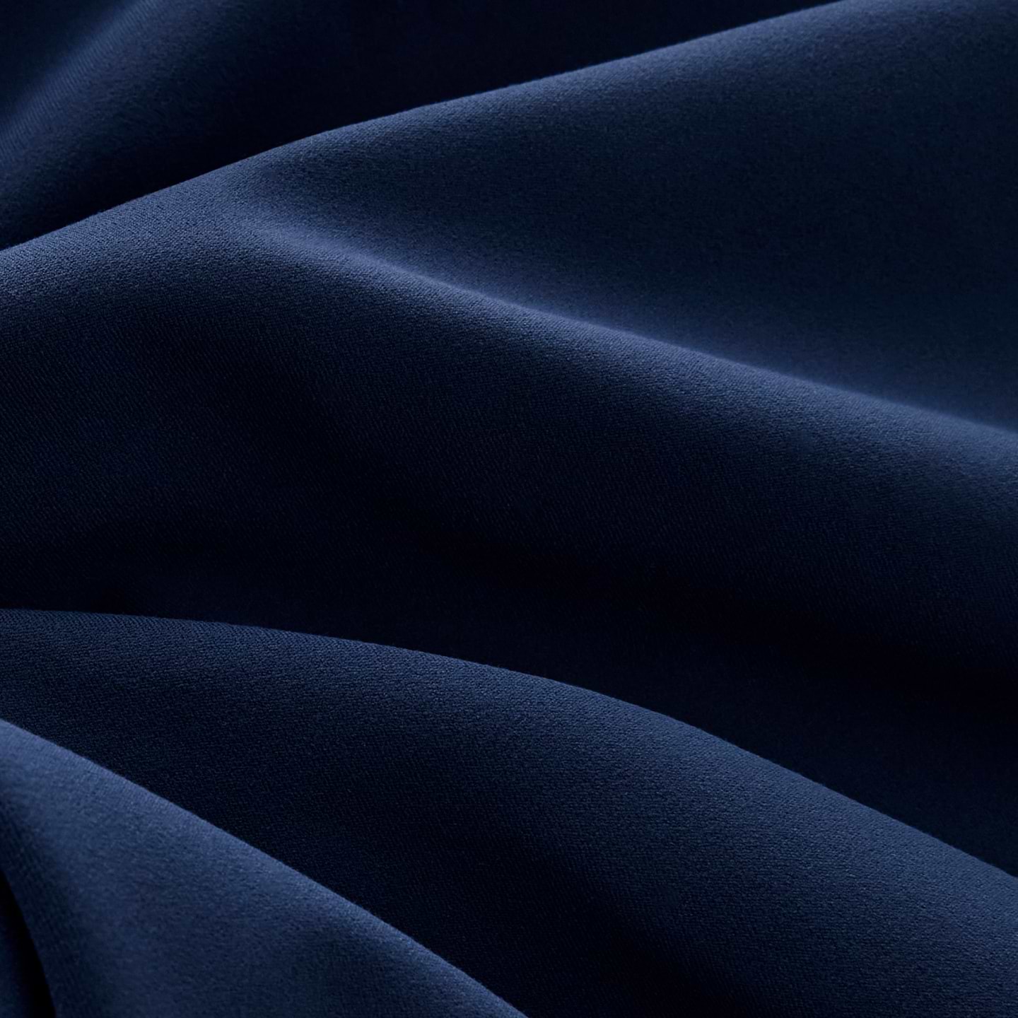 Close-up of navy blue fabric with soft, smooth folds and gentle shadows.