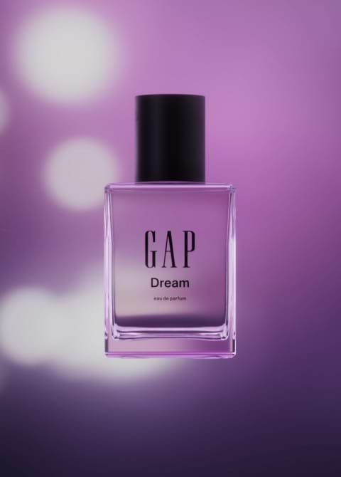 Clear rectangular bottle labeled “GAP Dream” eau de parfum against a purple bokeh background.