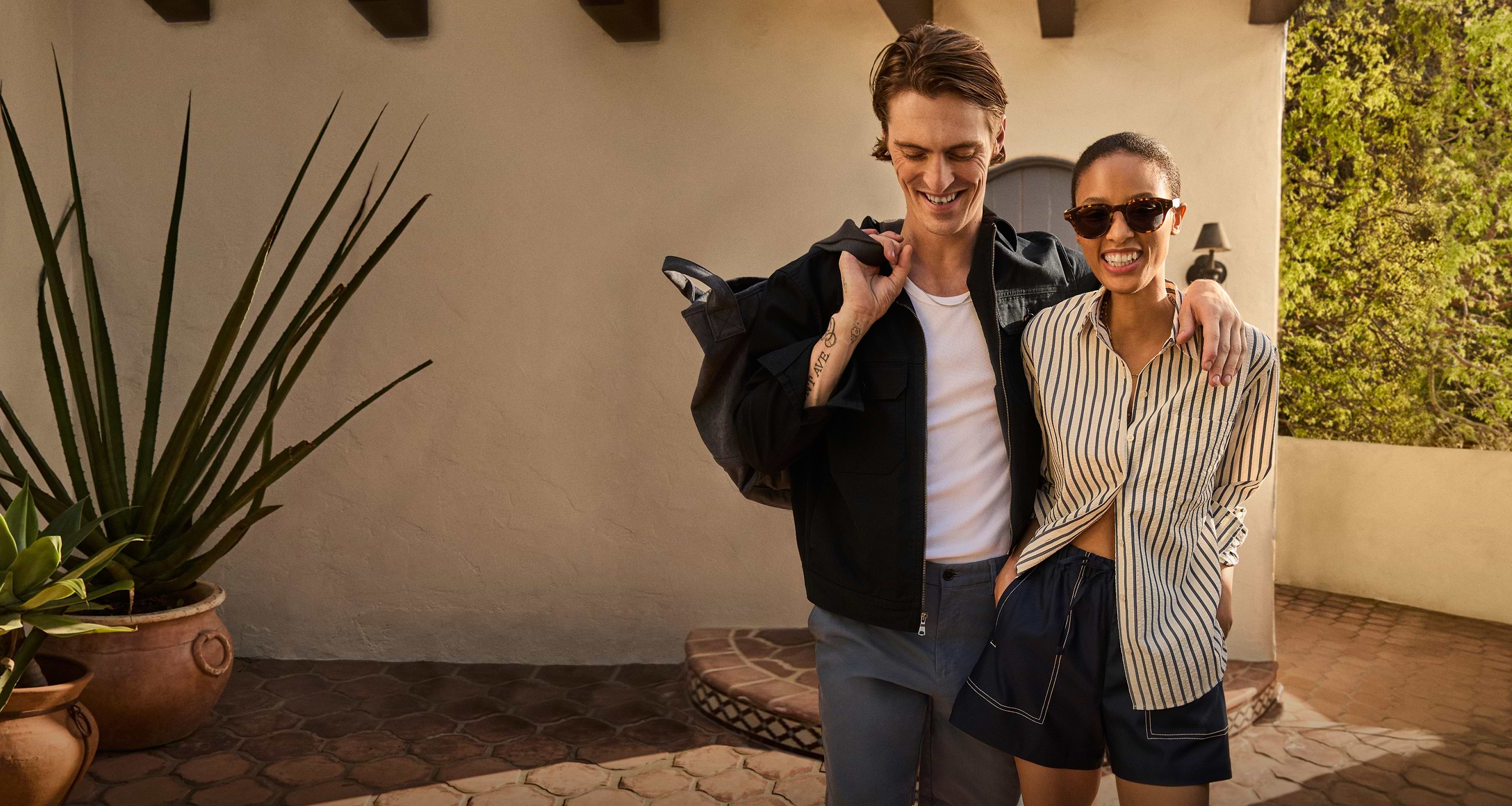 Man in black jacket, white shirt, and jeans. Woman in striped shirt and shorts.