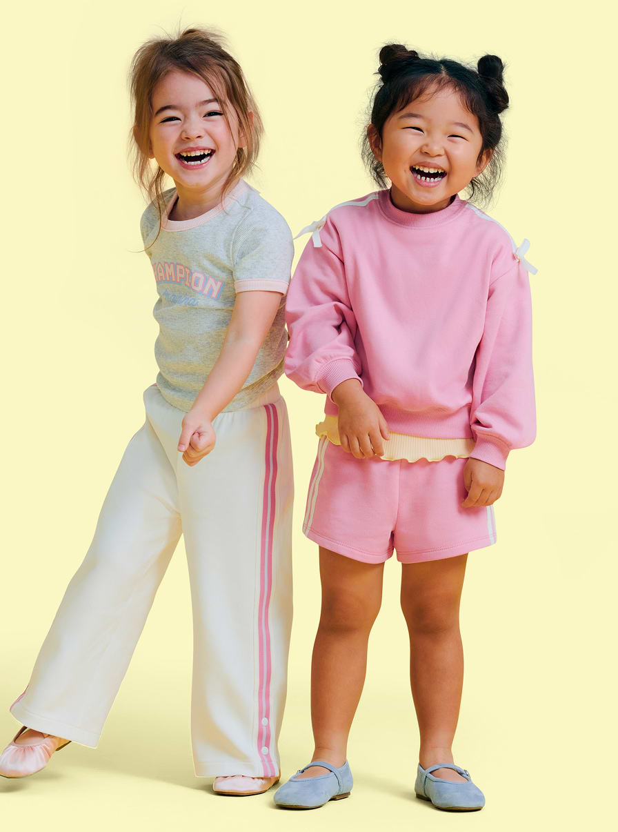 Two toddler girls wearing active tracksuits and shorts.