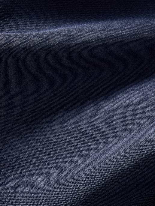 Close-up of dark navy fabric with soft diagonal folds and a subtle sheen.