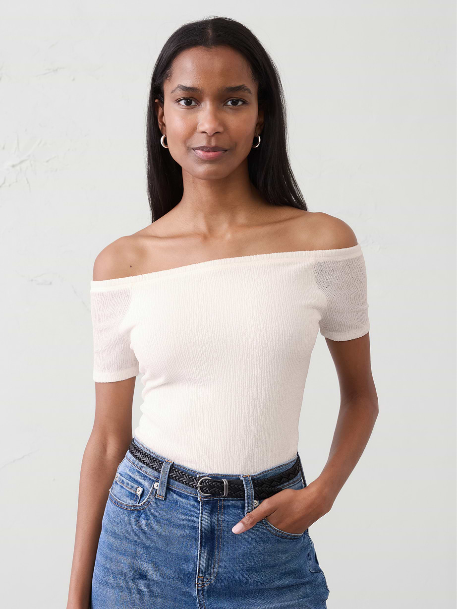 Woman in white off the shoulder top and jeans.