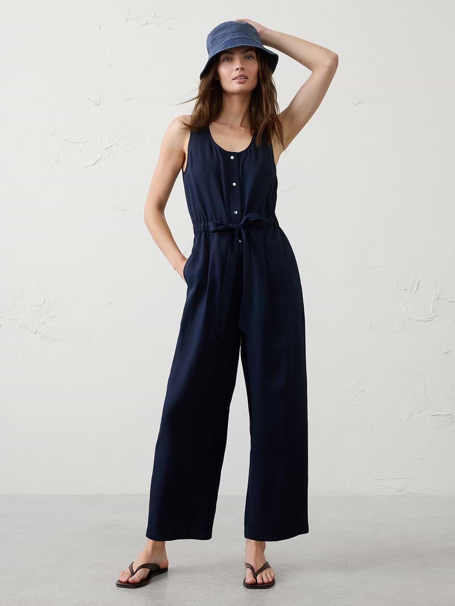 Woman in blue jumpsuit and bucket hat.
