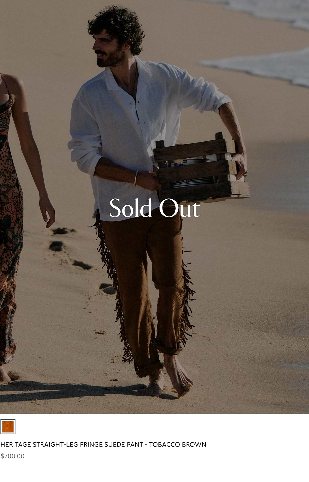 Person walking on a beach wearing tobacco-brown fringe suede pants; “Sold Out” text overlaid.
