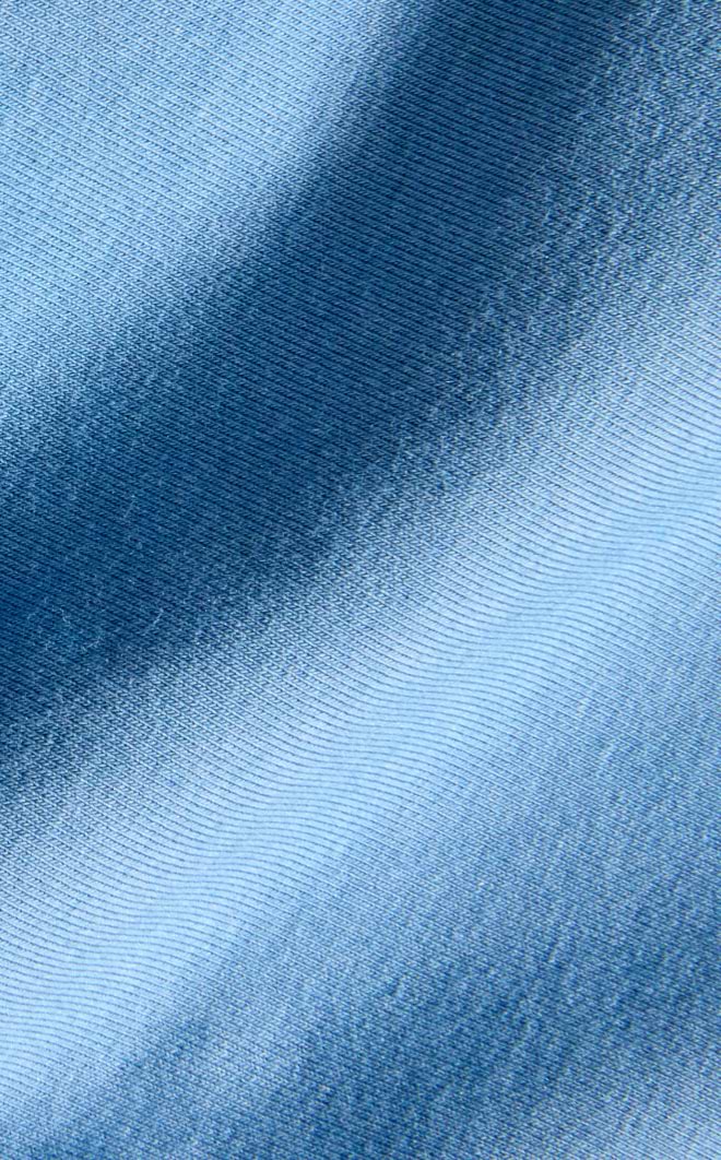 Close-up of blue fabric with a diagonal gradient and fine ribbed texture.