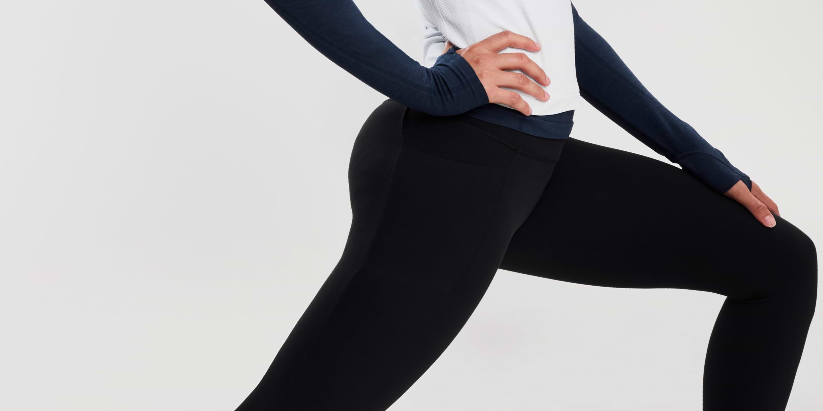 Close-up of a person doing a forward lunge, wearing black leggings and a white top with navy sleeves.