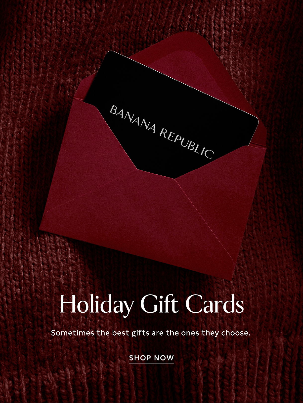Black Banana Republic gift card peeking from a red envelope on a red knit background; overlay text reads “Holiday Gift Cards… Sometimes the best gifts are the ones they choose. Shop Now.”