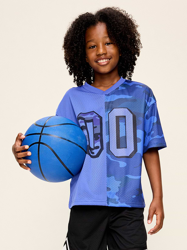 Smiling child holding a blue basketball, wearing a blue camo jersey with “00.”