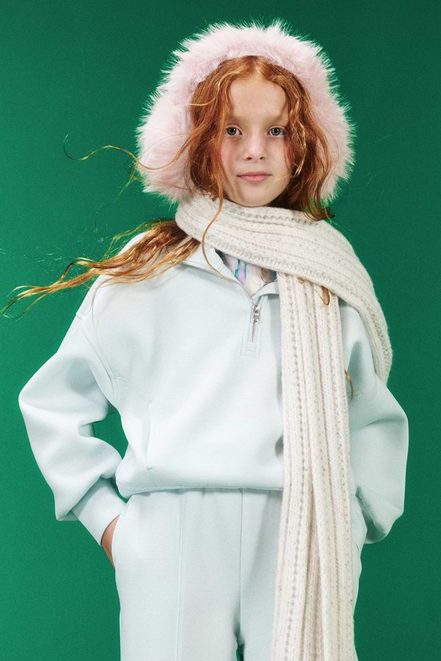 A young girl model wearing matching sweatshirt and sweatpants.