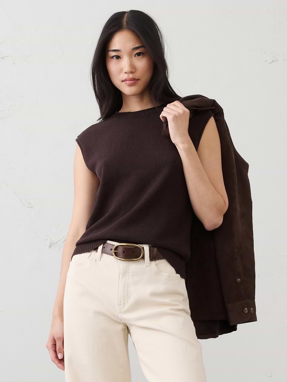 Woman in brown sweater top and tan jeans.