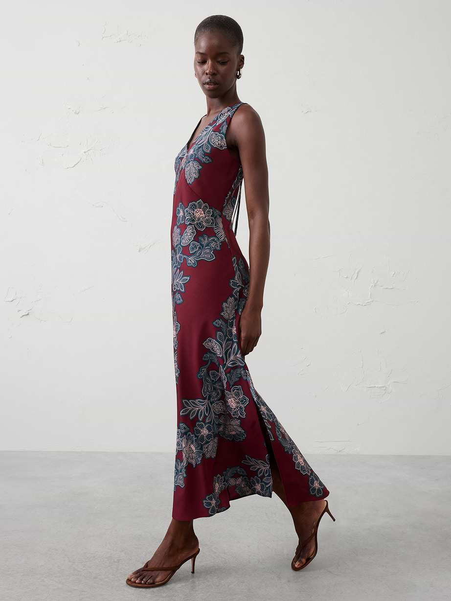 Side view of person in a sleeveless maroon floral maxi dress with side slit and heeled sandals.