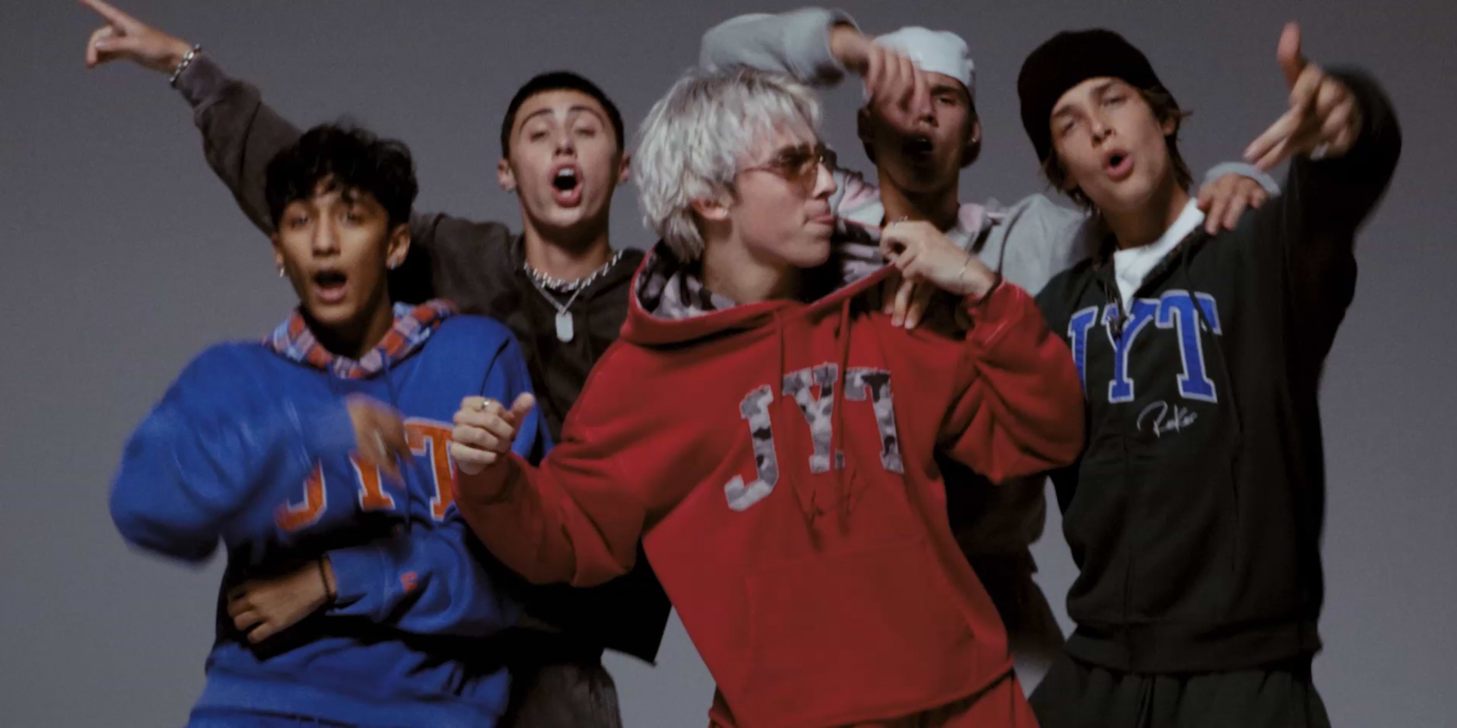 a group of young men in sweatshirts and hoodies posing for a picture