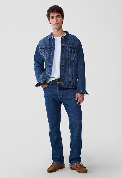 A male model wearing straight jeans and a beige jacket.